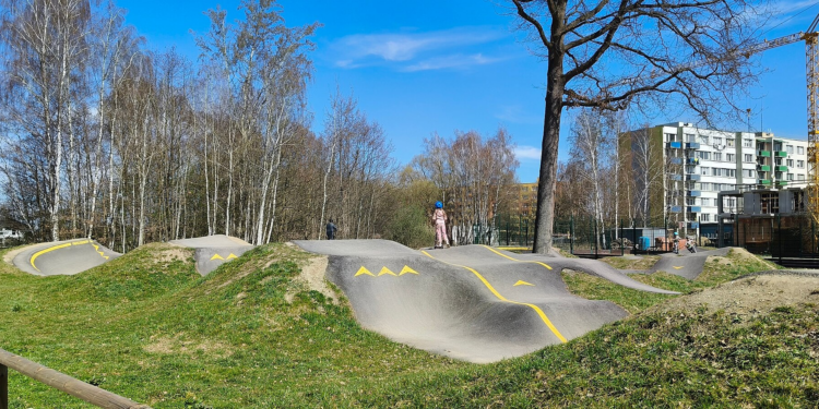 Pista de skatepark con rampas de hormigón y una zona de pumptrack con curvas peraltadas en un espacio al aire libre